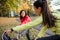 Two female runners stretching legs outdoors in park in autumn nature.