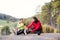 Two female runners stretching legs outdoors in park in autumn nature.