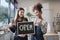 Two female shopkeepers show an open signboard in the refill store shop