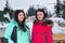 Two female in ski suits and with ski goggles standing snow-covered skiing town