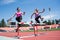 Two female sportswomen are jumping over an obstacle. Running with hurdles. Active lifestyle.