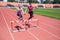 Two female sportswomen are jumping over an obstacle. Running with hurdles. Active lifestyle.