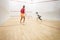 Two female squash players in action on a squash court