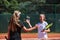 Two female tennis players shaking hands with smiles on a sunny day, exuding sportsmanship and friendship after a