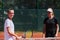 Two female tennis players shaking hands with smiles on a sunny day, exuding sportsmanship and friendship after a