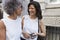 Two female work colleagues talking in the street, close up