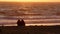 Two Females Sitting on Beach at Sunset