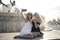 Two females taking a selfie while sitting on the fountain in the city