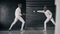 Two fencers man and woman have fencing match indoors