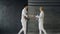 Two fencers man and woman shake hands each other at the end of fencing competition indoors