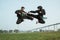 Two fighters wearing black pencak silat uniforms with flying kicks