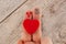 two fingers of the hand with painted faces male and female and a big red heart between them. wooden background. first