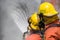 Two firefighter in helmet and oxygen mask spraying water to fire