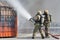 Two firefighters extinguishes fire from fire hose, using firefighting water-foam barrel with air-mechanical foam