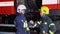 Two firefighters in protective clothing in helmets with fire engine, friendly handshake