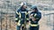 Two firefighters are smiling while petting a rabbit in the fire zone