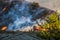 Two Firefighters Stand Next to Bulldozer with Hillside Burning in Background during California Fire