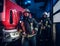 Two firemen wearing protective uniform standing next to a fire truck in a garage of a fire department.