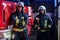 Two firemen wearing uniform standing next to a fire engine in a garage of a fire department, smiling and looking at a