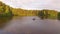 Two fisherman in rubber boat floats with white swan. Drone aerial shot. Friends relaxes in boat on lake in sunny forest