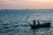 Two fishermen collecting fishing net to their small boat