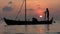 Two fishermen wash old boat at sunset in the Indian Ocean. Slow motion