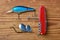 two fishing lures and multifunctional swiss army red knife isolated on wooden background