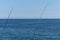 Two fishing rod against blue ocean or sea background, copy space. Waiting for biggest haul. Meditative relax sport