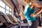 Two fit women running on treadmills in modern gym