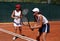 Two fit, young, healthy women playing doubles at tennis in the sun