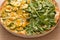 Two flavor pizza: Arugula and zucchini with corn kernels.