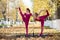 Two flexible Caucasian women stand by a portable pole of autumn leaf fall background