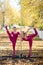 Two flexible Caucasian women stand by a portable pole of autumn leaf fall background