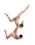 Two flexible girls gymnasts in beige leotards are performing exercises upside down using support and posing isolated on