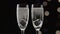 Two flutes of champagne with transparent pieces of ice on the bottom.Bokeh blinking black background. Close up