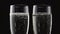 Two flutes of chilled sparkling wine. Bokeh blinking black background. Close up