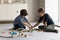 Two focused kids building toy railroad on floor, completing construction