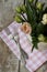 Two forks lie on pink napkin next to a vase of delicate pink tulips. The composition stands on a wooden old background