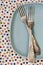 Two forks lying on blue plate on bright background