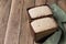 Two forms of Raw rye-wheat bread with flour sourdough and a green towel on the table. Brown wooden background.