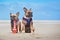 Two French Bulldog dogs on holidas sitting on beach in front of clear blue sky