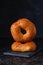 Two fresh bagels with sesame crust on a black slate board on a black concrete background