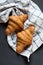 Two fresh croissant lying on a blackboard. Also, there is twisted linen towel.