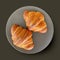 Two fresh croissants on grey plate