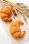 Two Fresh Croissants with spikelets of wheat on paper