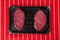 Two fresh fillet steaks on a plastic tray on a red and white butcher apron. Meat and retail industry concept. Premium cut of beef