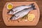 Two fresh moronidae fish on cutting board with ingredients