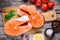 Two fresh raw salmon steaks with salt, peppers, lemon, tomatoes and dill