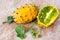 Two fresh ripe kiwano with vine and leaves, Cucumis metuliferus, on ceramic background