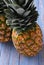 Two fresh ripe pineapples on rustic wooden blue table closeup